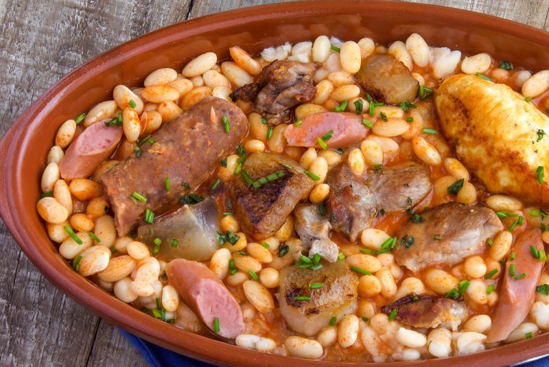 Cassoulet symbolizes southwestern French cuisine, known for its robust flavors and slow-cooked comfort food.